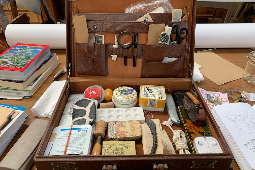 Indiana Jones-style briefcase with manifying glass, compass, thread, brushes, palette knives.