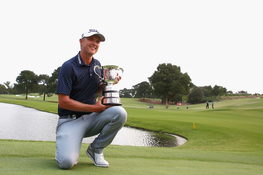 A male golfer holds a trophy as he celebrates winning the Australian Open.