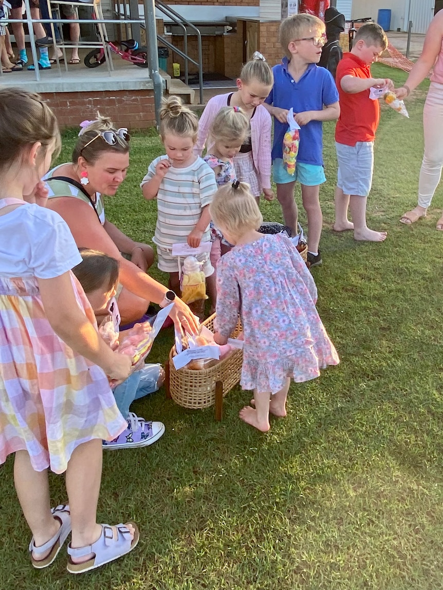 Children and parents gather around a basket full of stuffed toys