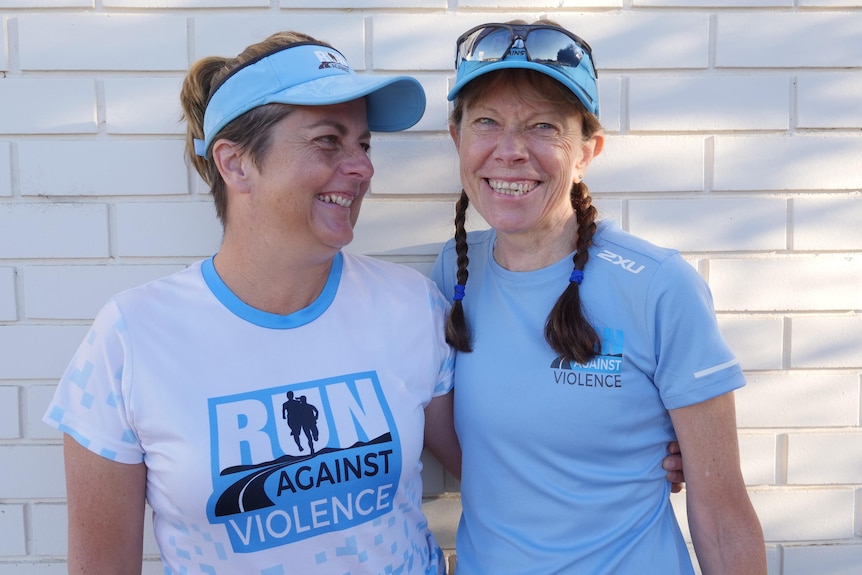 Two woman wearing blue and smiling.