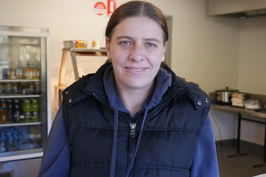 A woman standing in a football ground canteen. 