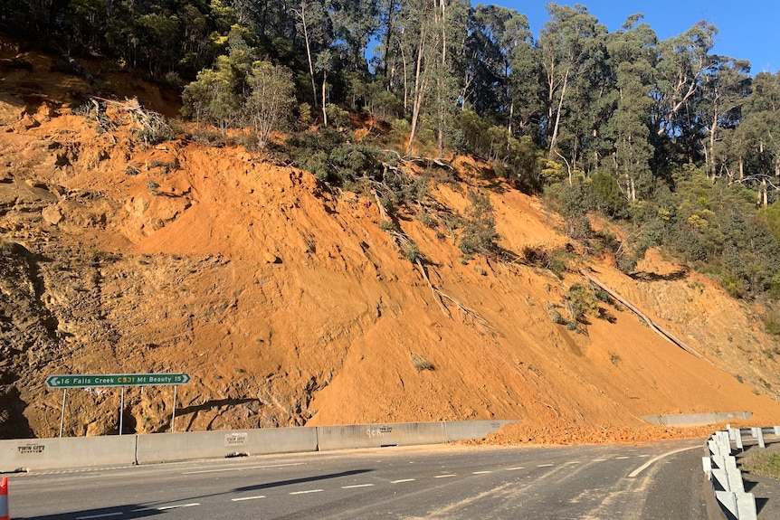 Road covered in rocks and orange dirt.