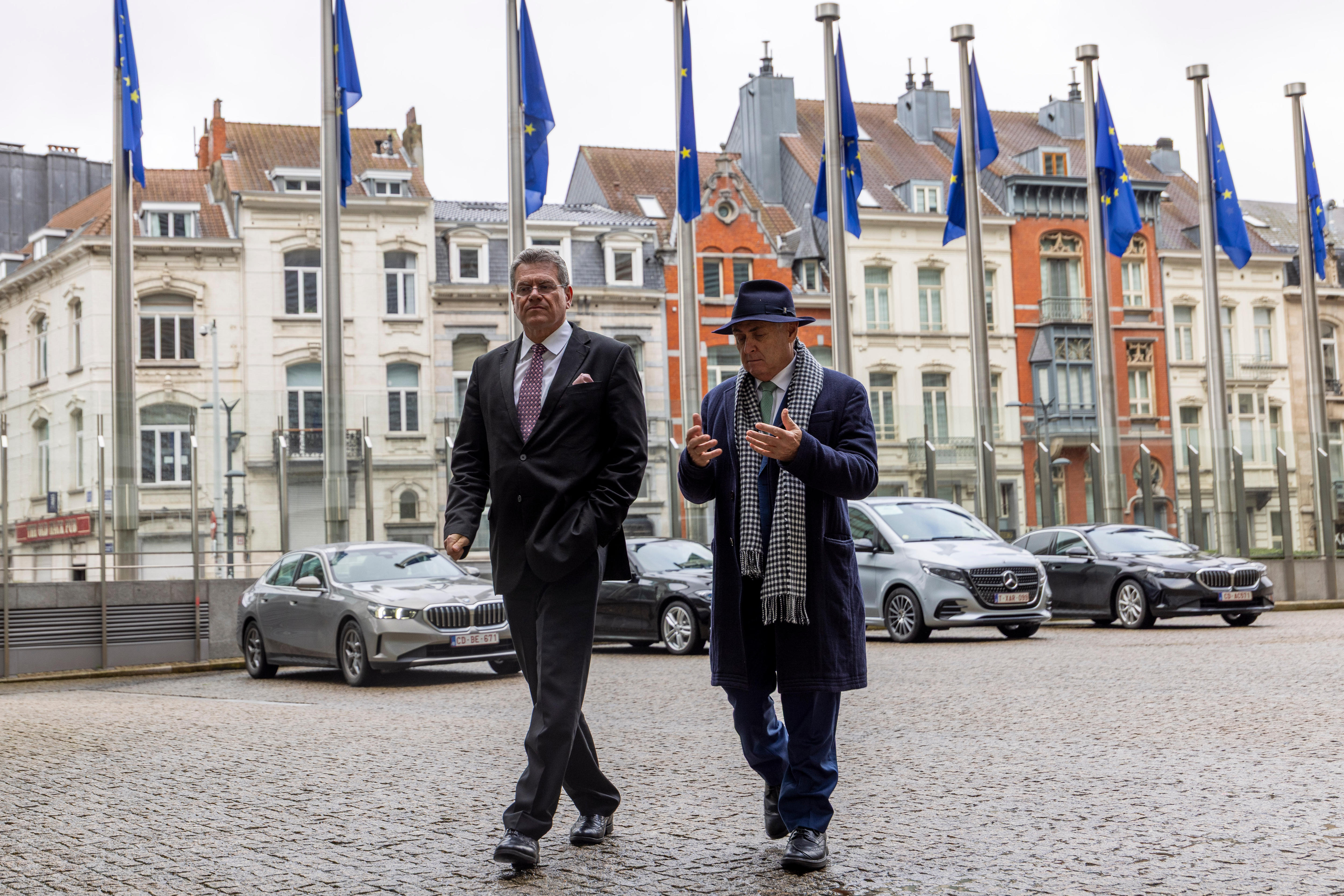 two men walk near flags.