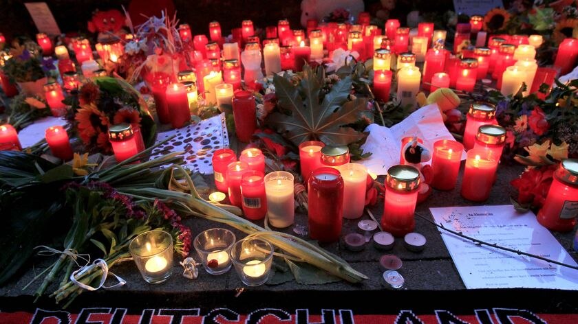 A soccer scarf is placed amid a sea of candles and flowers in Duisburg