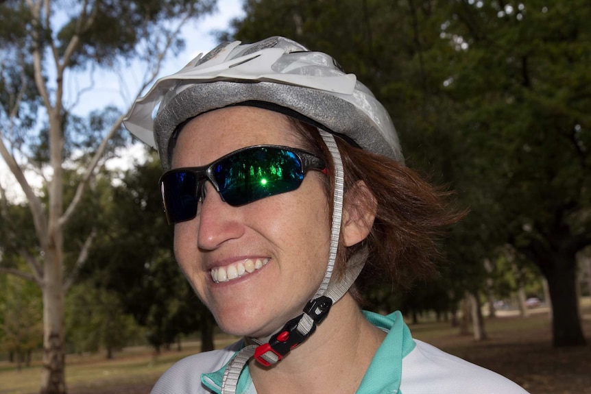 Close up of a woman wearing reflective sunglasses and a bike helmet