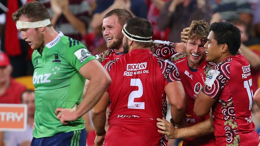 The Reds' Dom Shipperley celebrates with teammates after scoring against the Highlanders.