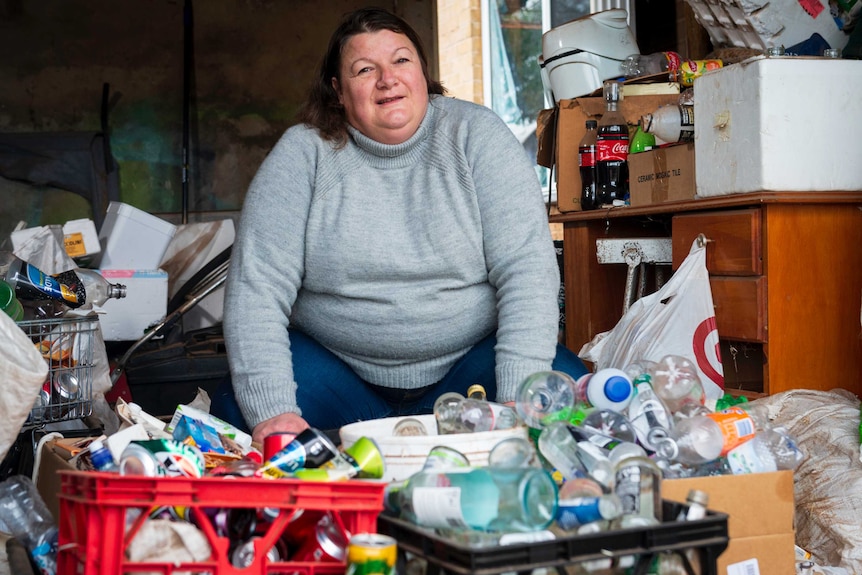 Tracey Phillips sits behind her collection of bottles and cans