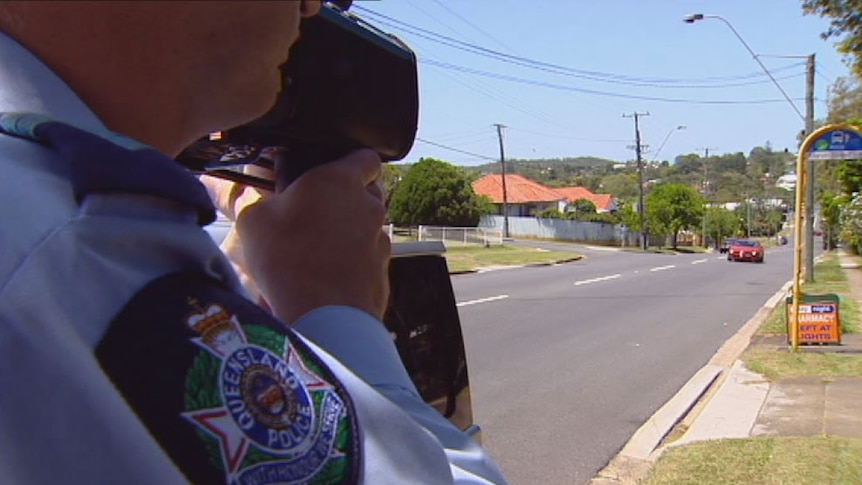 Qld police officer with speed gun pointing at car in Brisbane