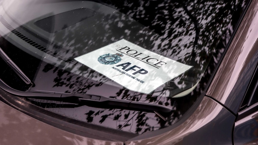 Printed sign reading Police - AFP Australian Federal Police - displayed in window of car