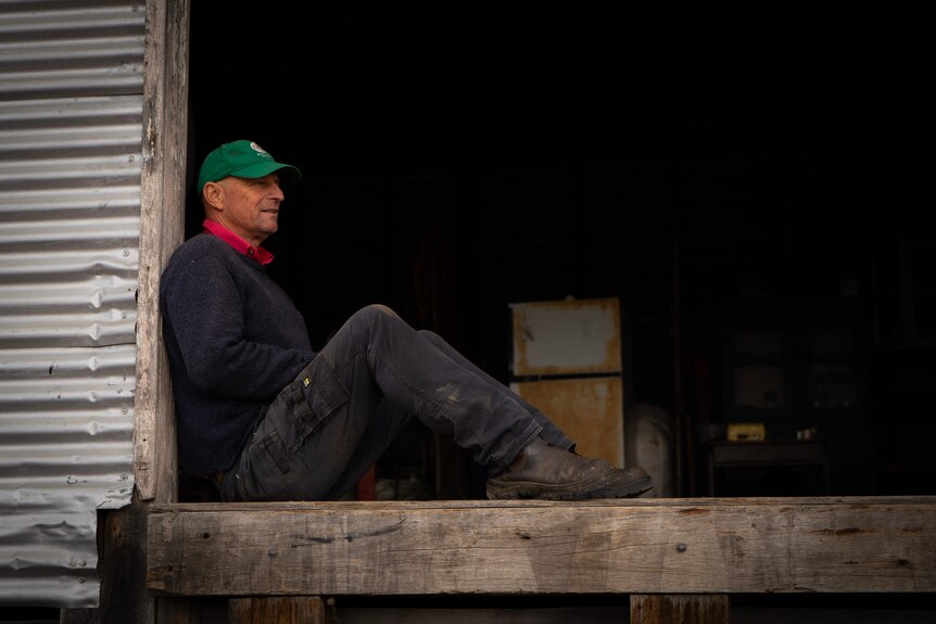 A man sitting in a farming shed.