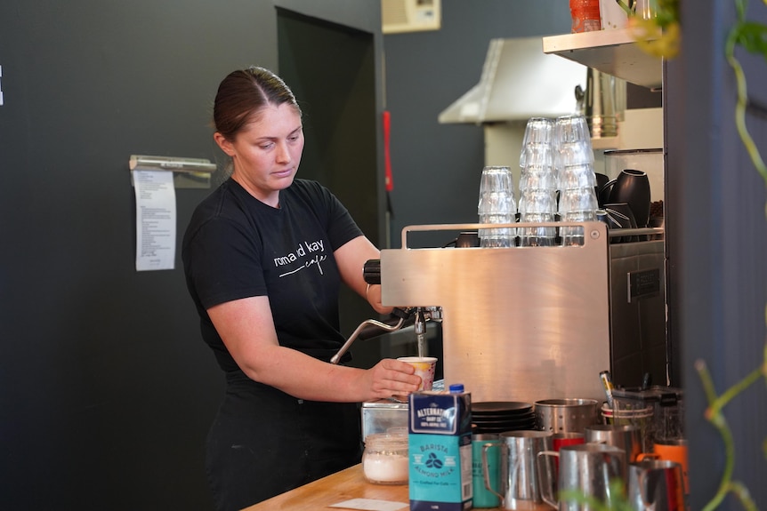 A woman named Chloe McDougall makes a coffee at a coffee machine.