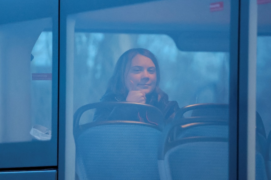 Greta Thunberg gestures as she sits alone in a bus on the day of a protest.