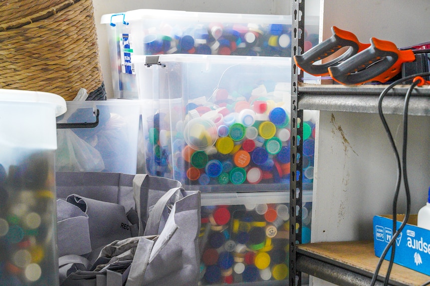 Large storage bins filled with colorful bottle lids stacked on top of each other.