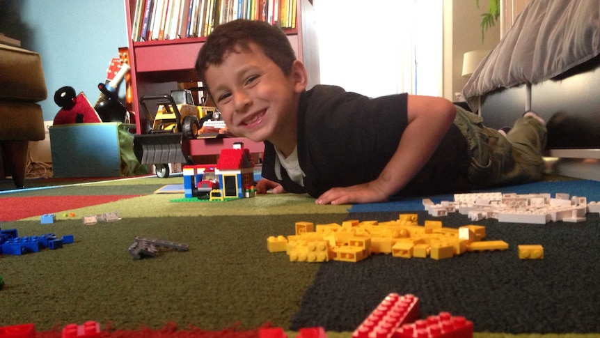 A boy on the floor playing Lego.