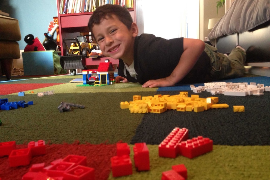 A boy on the floor playing Lego.