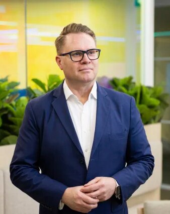 A man wearing glasses and a navy blue suit 