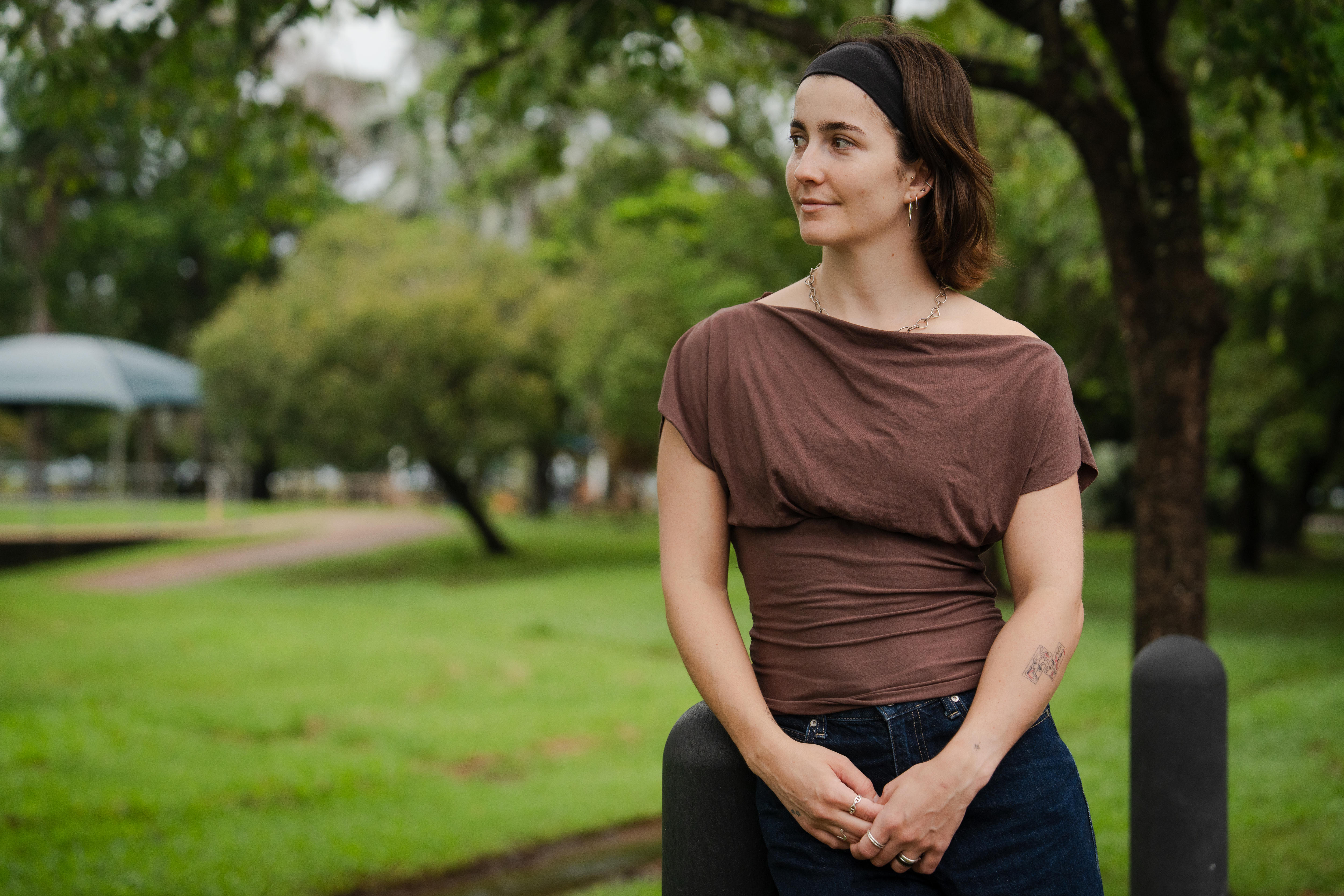 Una mujer se apoya en un poste en un parque público.
