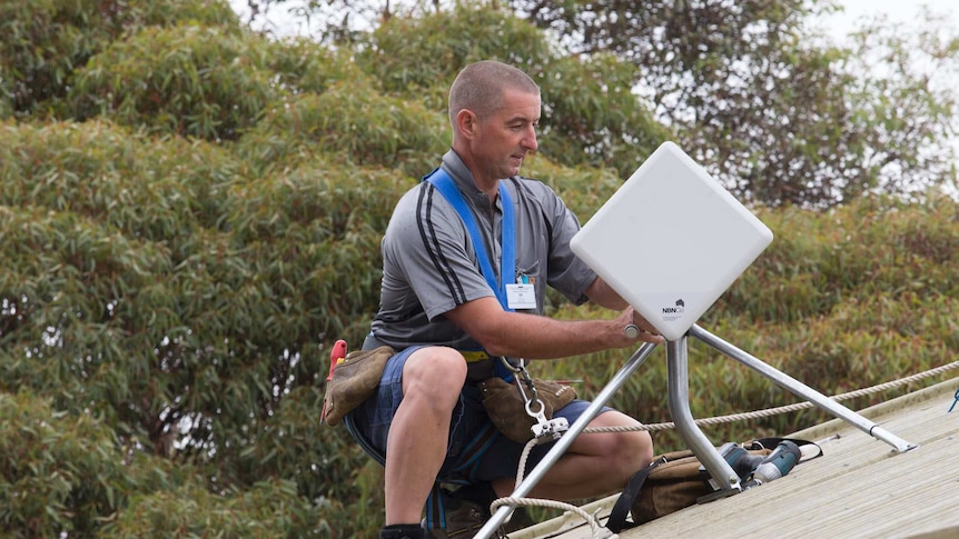 Technician installs a NBN fixed wireless received on a roof