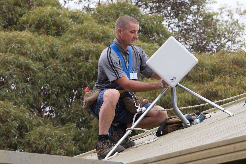 Technician installs a NBN fixed wireless received on a roof