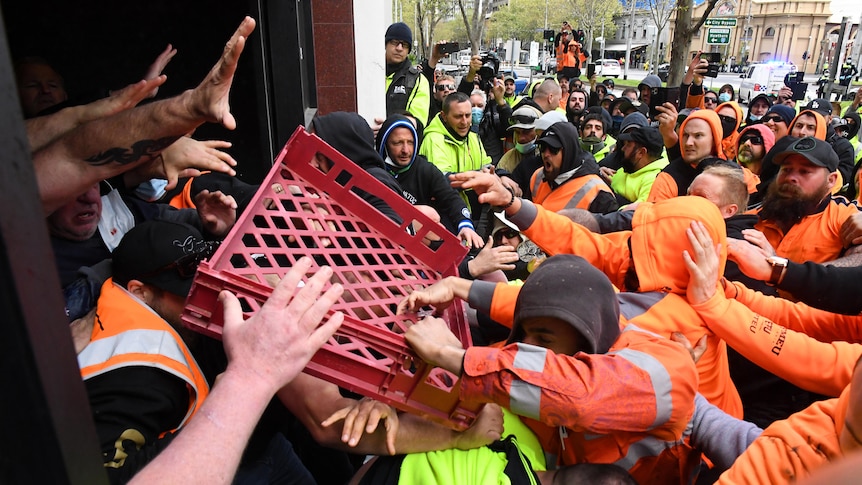 Protesters throw a milk crate at security