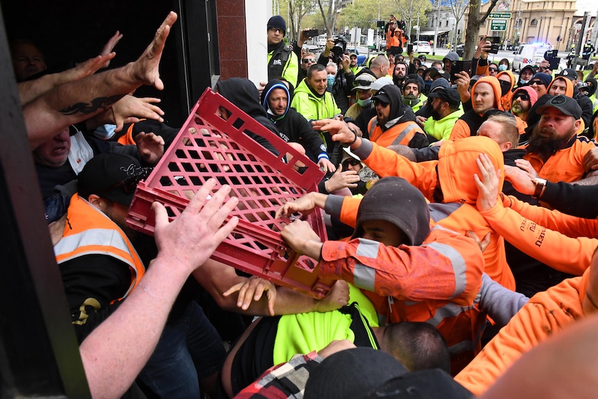 Protesters throw a milk crate at security.