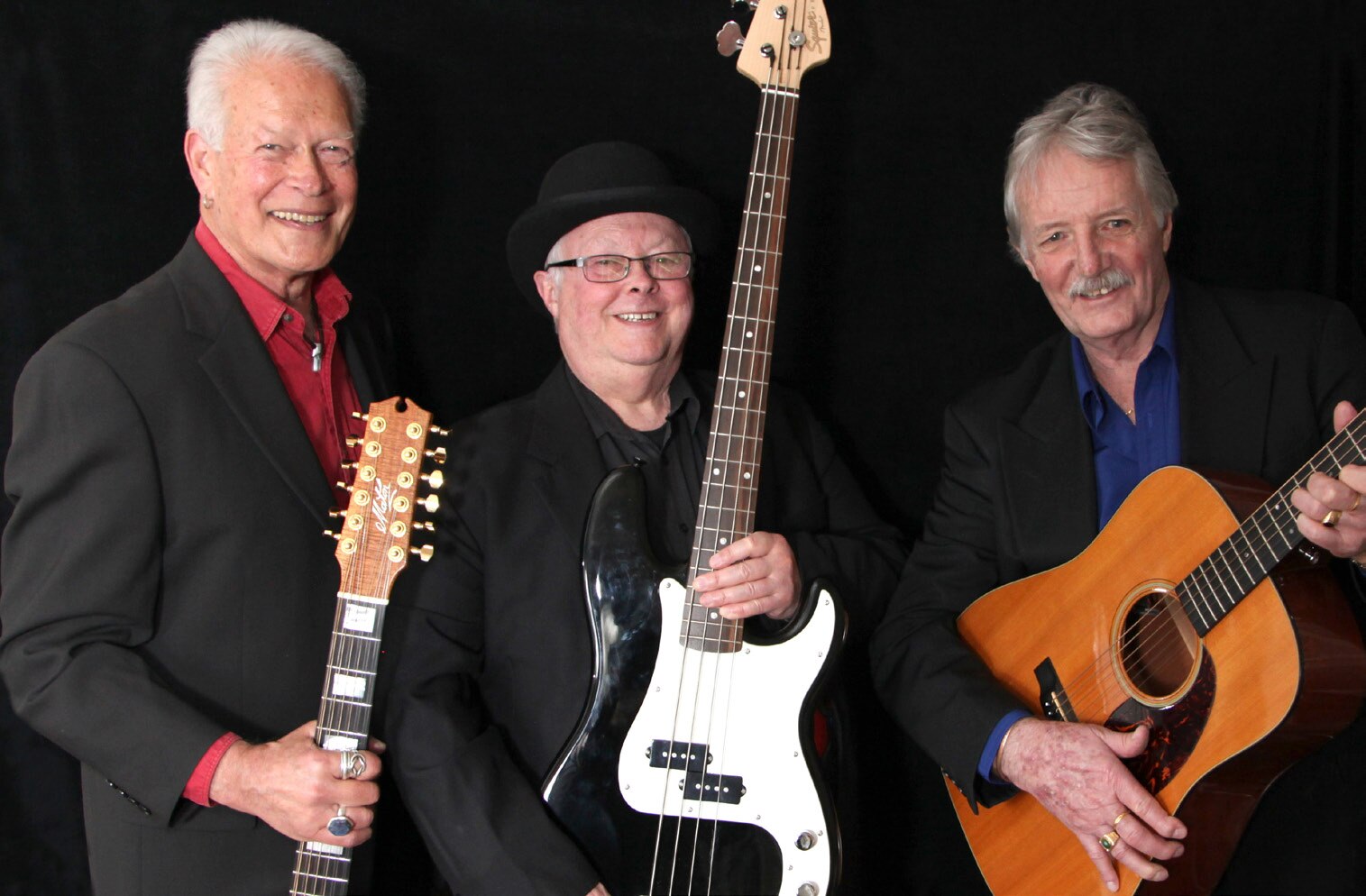 Band members standing and holding guitars against a black background 