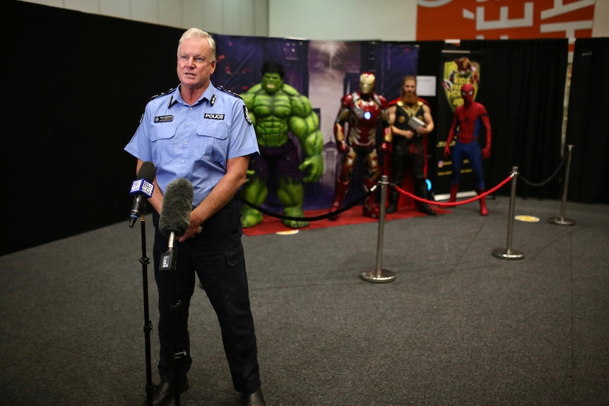 WA Vaccine Commander Gary Dreibergs talking at a media conference in front of Marvel superheroes.