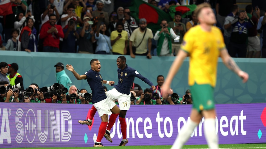 Kylian Mbappe and Ousmane Dembele chest each other after a France goal. Socceroos' Harry Souttar is blurry in the foreground.