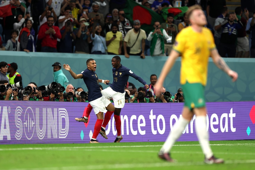 Kylian Mbappe and Ousmane Dembele chest each other after a France goal. Socceroos' Harry Souttar is blurry in the foreground.