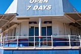 A dilapidated shop front with an 'open seven days' sign