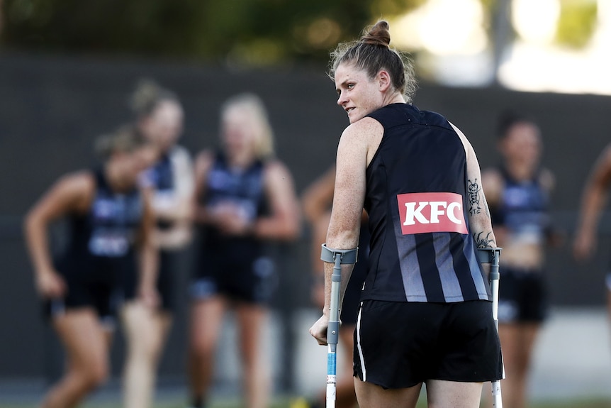 Bri Davey walks on crutches at Collingwood training