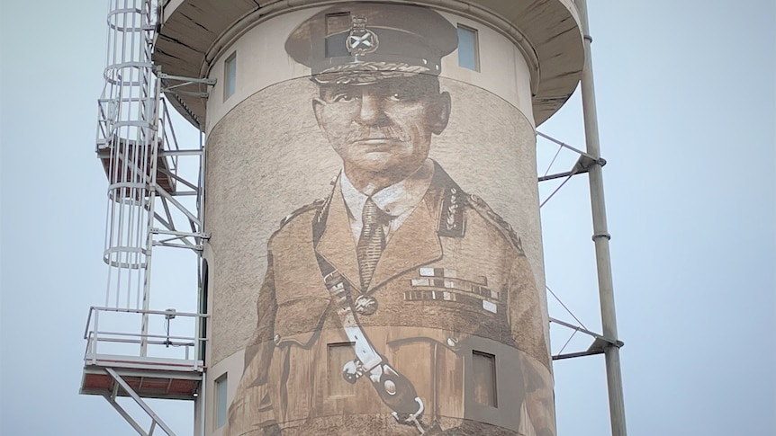 Water tower with man painted on it