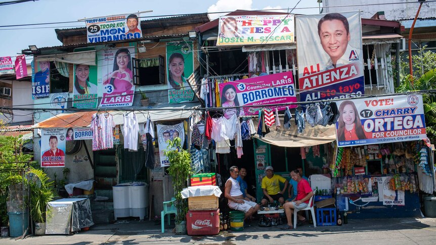Shopfronts adorned with bright candidate posters and laundry hanging to dry.