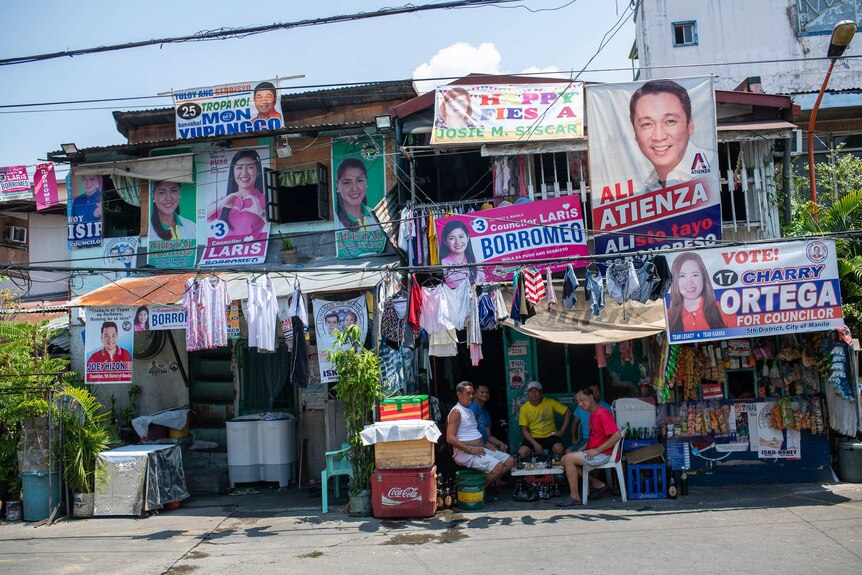 Shopfronts adorned with bright candidate posters and laundry hanging to dry.