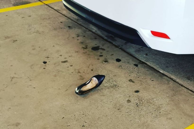 A woman's high-heeled shoe in a carpark bay.
