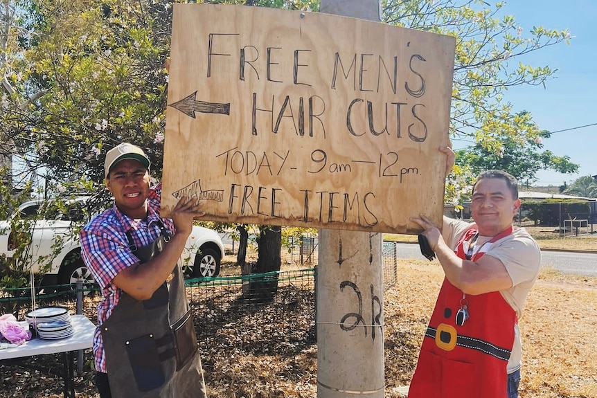 two men hold a sign that reads free haircuts