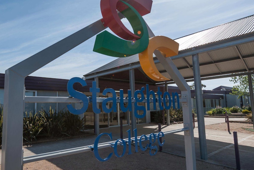 A sign outside a school says Staughton College on a sunny blue sky day.