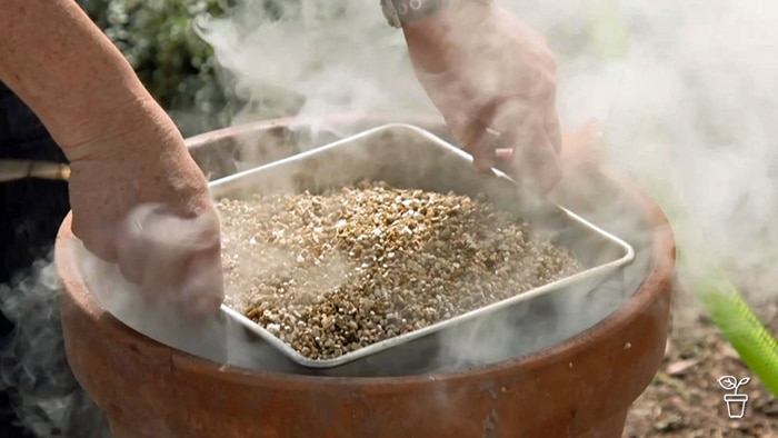 Tray filled with potting medium being lowered into a smoking terracotta pot