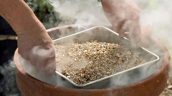 Tray filled with potting medium being lowered into a smoking terracotta pot