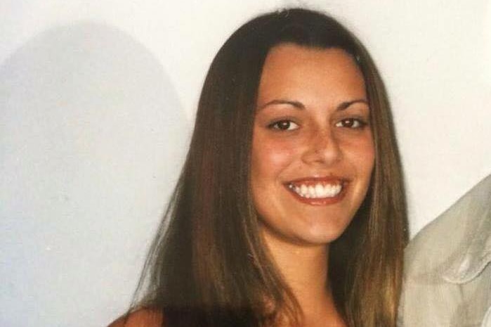 A woman with long brown hair smiles at the camera