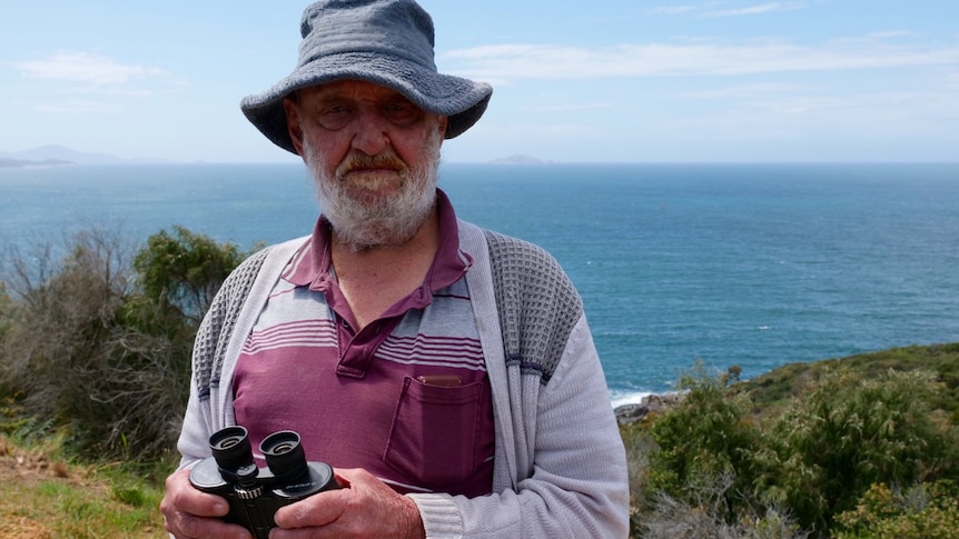 Mick Stubbs holding a pair of binoculars and looking for whales off the Albany coast