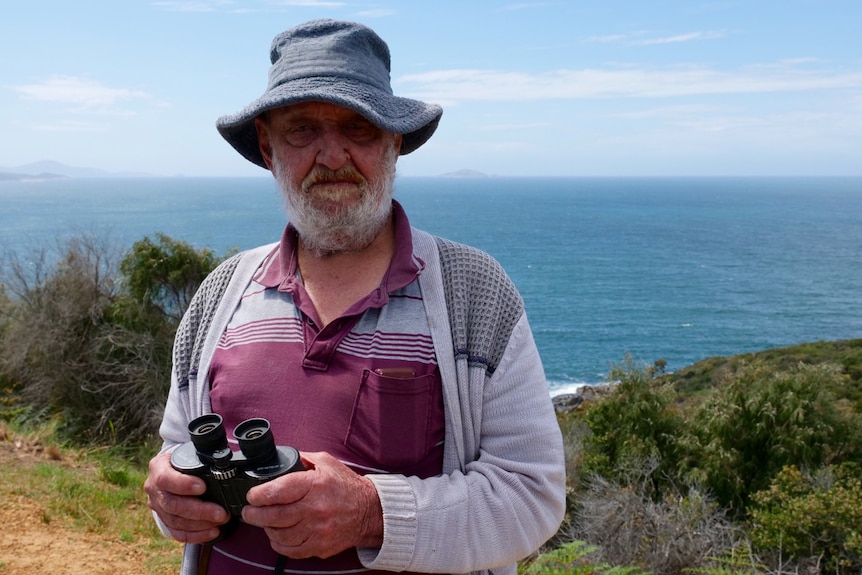 Mick Stubbs holding a pair of binoculars and looking for whales off the Albany coast