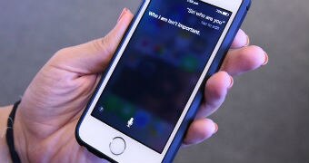 A close-up of a woman's hand holding onto an iPhone as she speaks to Siri.