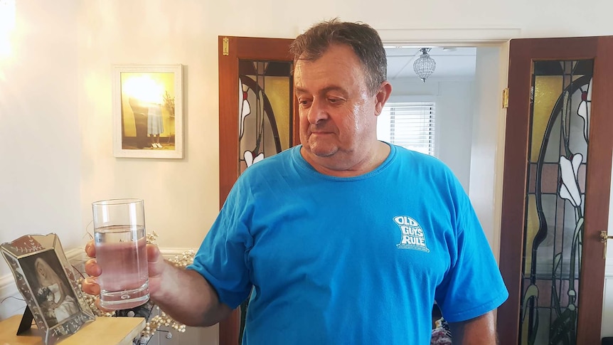 Ron Holzhimer holds a glass of water in his Bundaberg home.