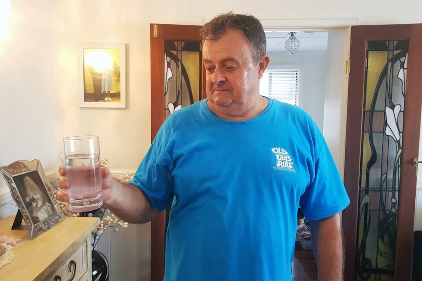 Ron Holzhimer holds a glass of water in his Bundaberg home.