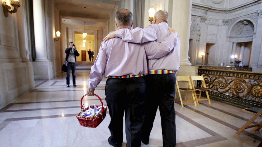 Two men holding hands with their backs to the camera walking away to get married.