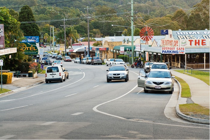 Cars driving along the main street of a country town.