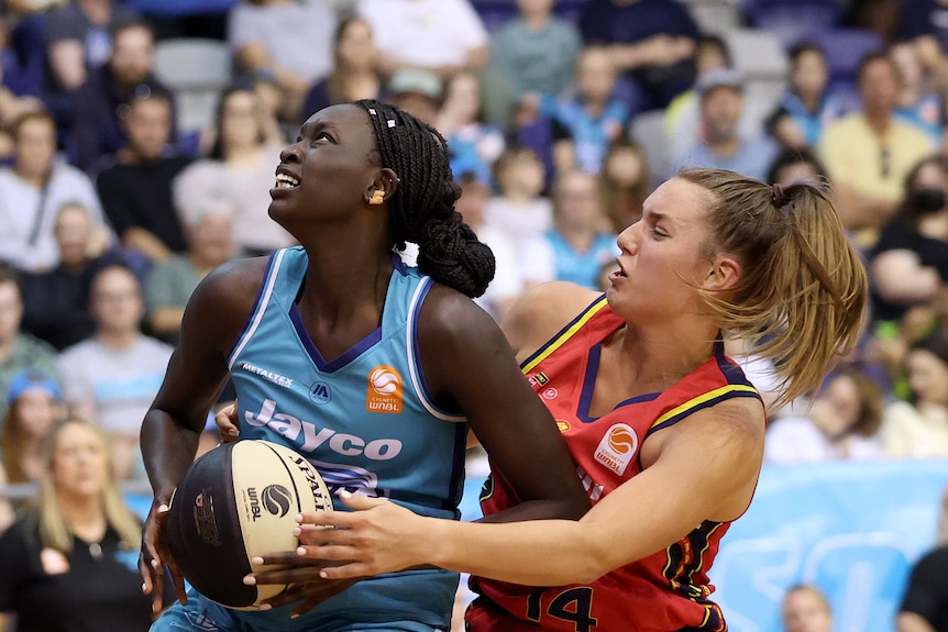 Isobel Borlase of Adelaide Lightning defends Nyadiew Puoch of Southside Flyers in the WNBL.