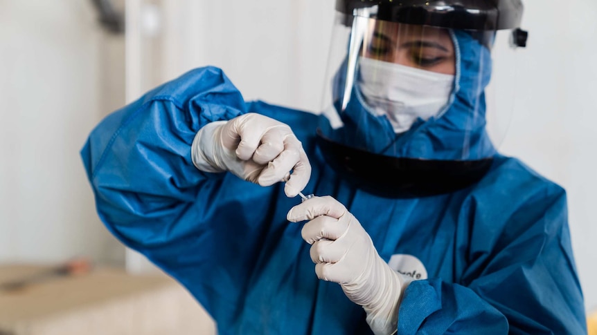 An Australian Clinical Laboratories worker in Perth places a nasal swab into a vial for COVID-19 testing.