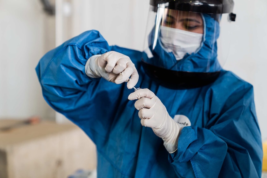 An Australian Clinical Laboratories worker places a nasal swab into a vial for COVID-19 testing.